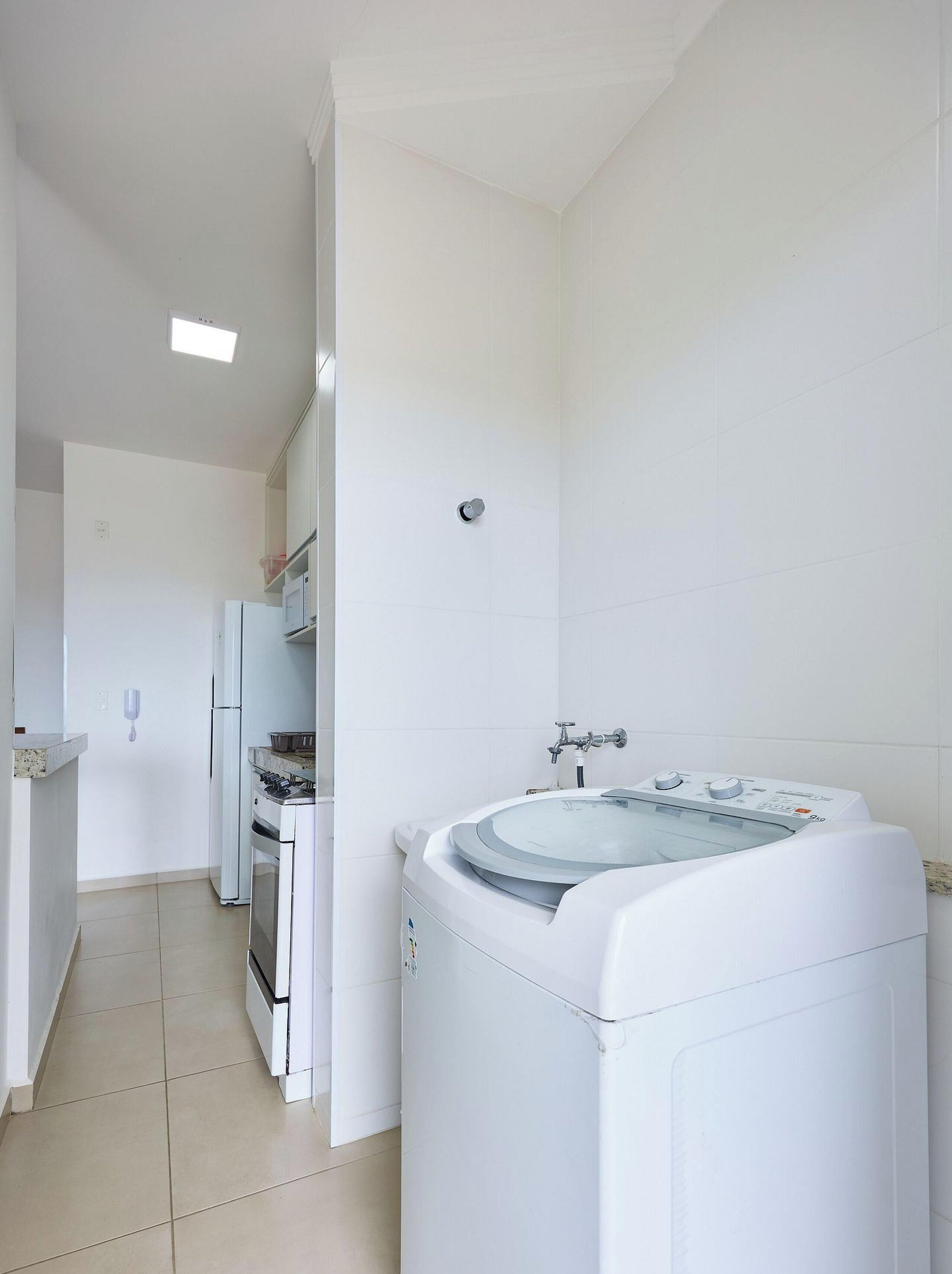 A kitchen with white appliances, including a washing machine, a refrigerator, and a stove.