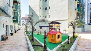 Ein Spielbereich für Kinder mit Rutsche, Schaukeln und einer kleinen Spielhaus-Konstruktion.