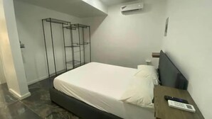 Een slaapkamer met een bed, een nachtkastje, een afstandsbediening en een airconditioning.