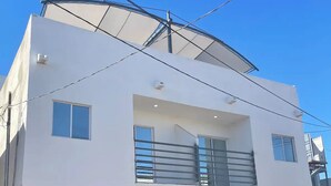 Een modern herenhuis met garage, een auto in de garage, en een helderblauwe lucht.