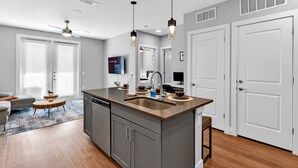 A modern kitchen with a central island, grey cabinets, and pendant lighting. - Cozy Comfort1bd Attached Garage+Desk+Pool+Gym (Fort Worth)