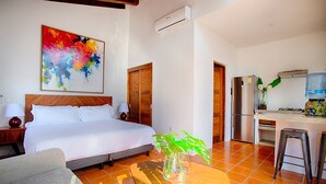 A hotel room with a bed, a desk, a chair, a water dispenser, and a refrigerator.