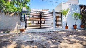 A gated residential area with a white building, a black metal gate, and potted plants.