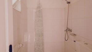A shower with a handheld showerhead and a wall-mounted faucet.