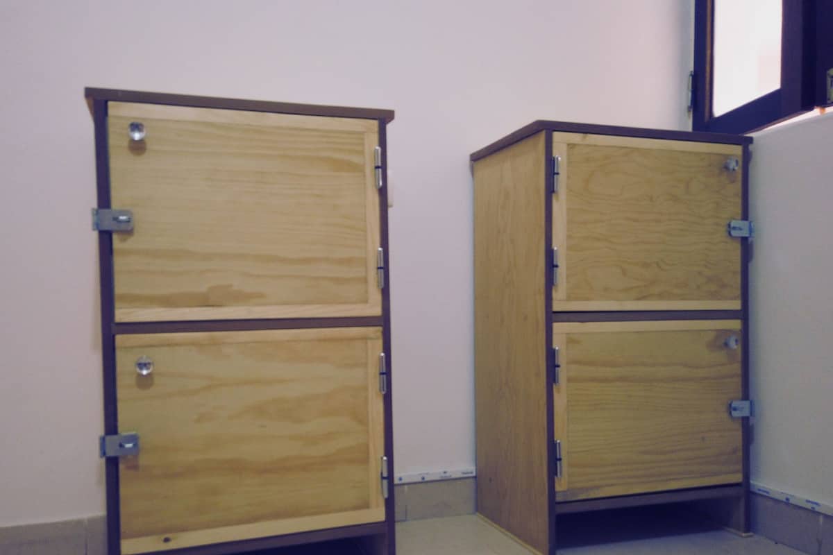 Two wooden cabinets with metal hinges and latches, placed against a wall in a room with tiled flooring.