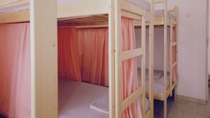 A room with bunk beds, each with a mattress and a wooden frame.