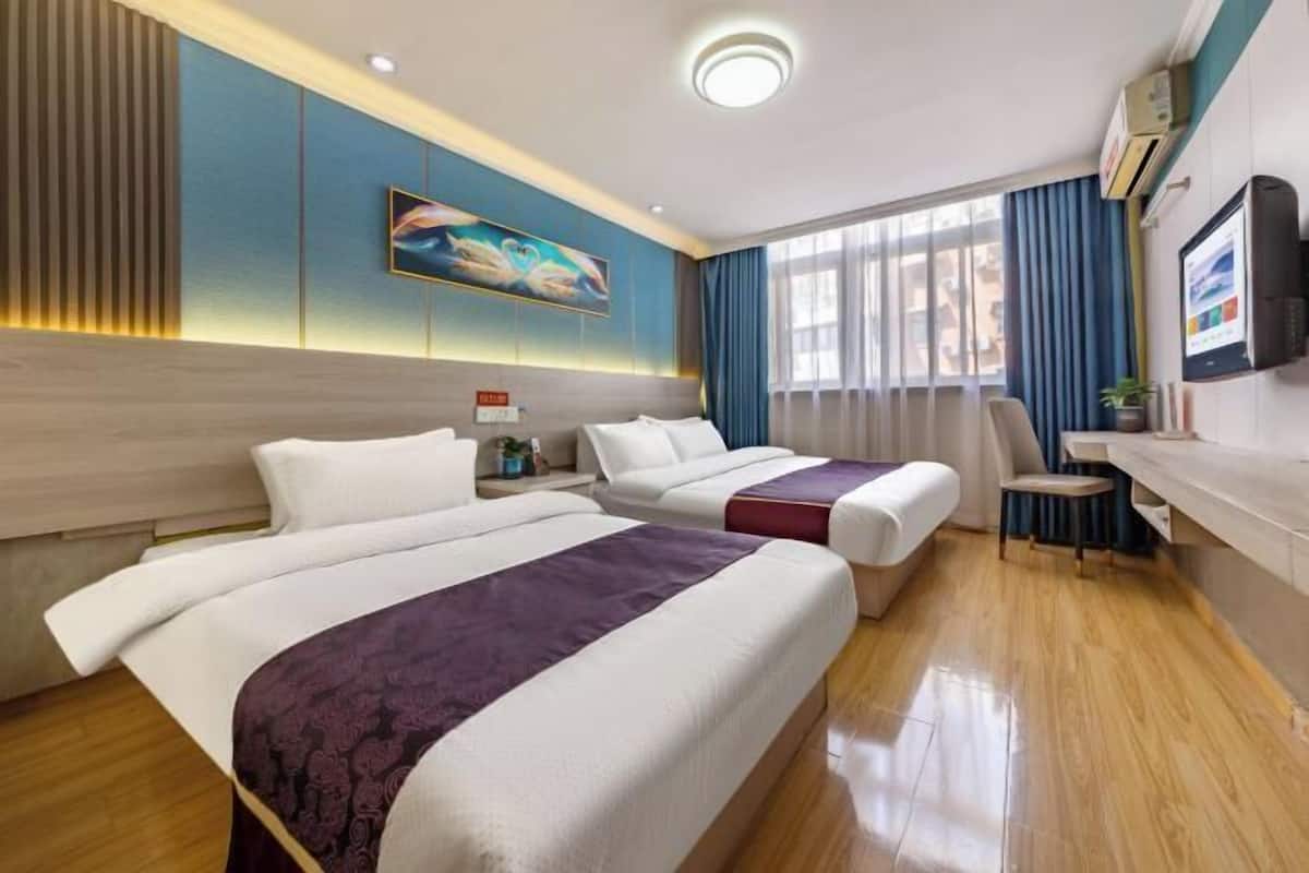 A hotel room with two beds, a desk, a chair, a TV, and a painting on the wall.