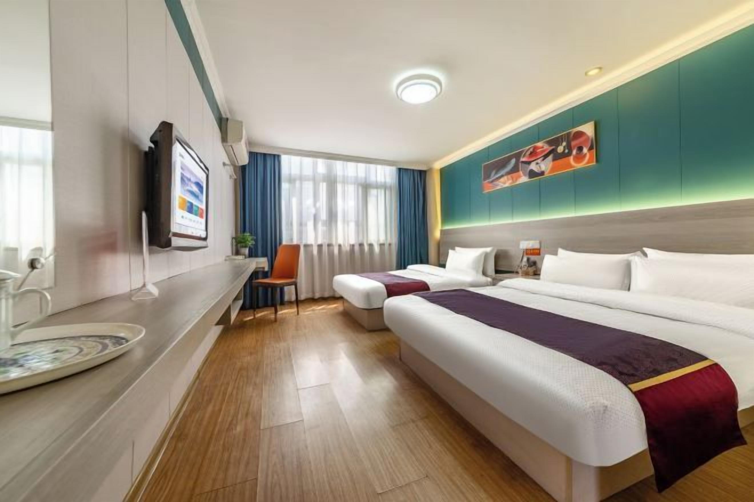 A hotel room with two beds, a desk, a TV, and a painting on the wall.