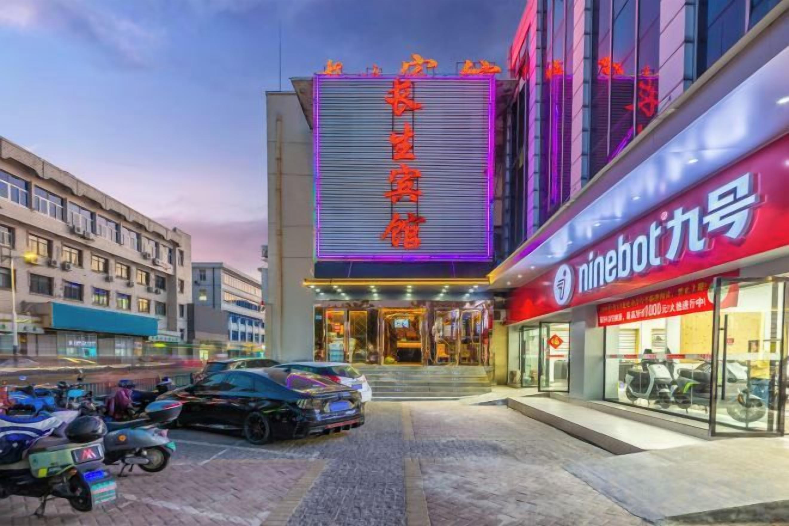 A building with a large illuminated sign, a storefront with signage, and parked motorcycles.