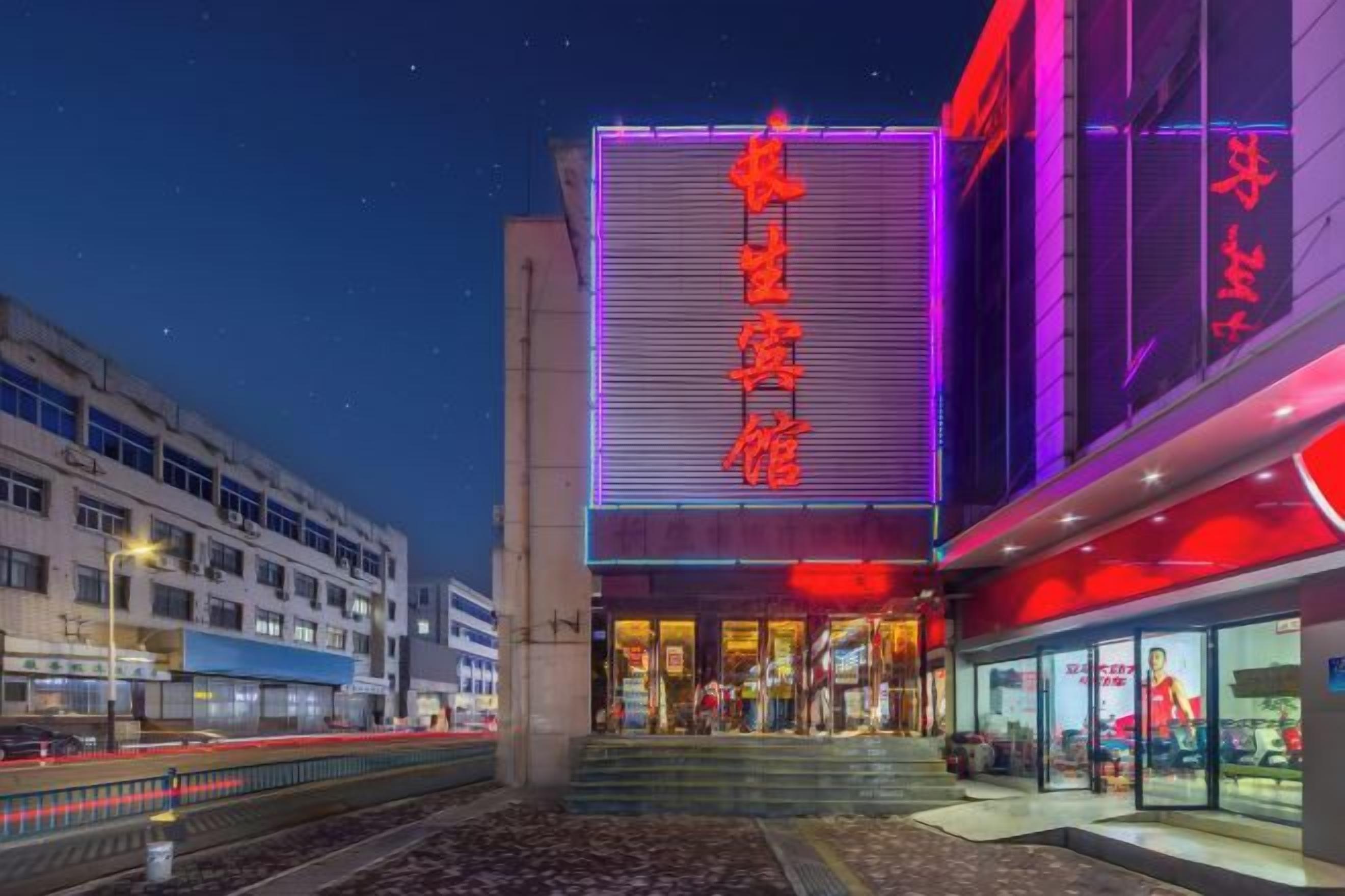 A building with a large illuminated sign, a staircase leading to the entrance, and a modern architectural design.