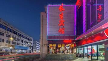 A building with a large illuminated sign, a staircase leading to the entrance, and a modern architectural design.