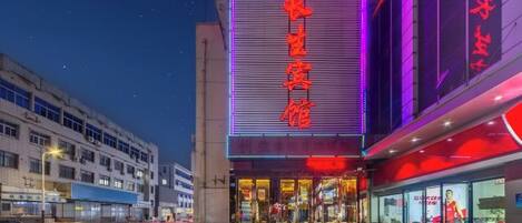 A building with a large illuminated sign, a staircase leading to the entrance, and a modern architectural design.