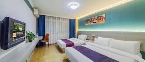A hotel room with two beds, a desk with a computer, a chair, and a window with curtains.
