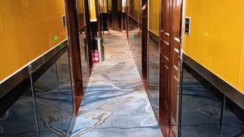 A hallway with a marble floor, yellow walls, and a door at the end.