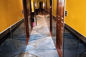 A hallway with a marble floor, yellow walls, and a door at the end.