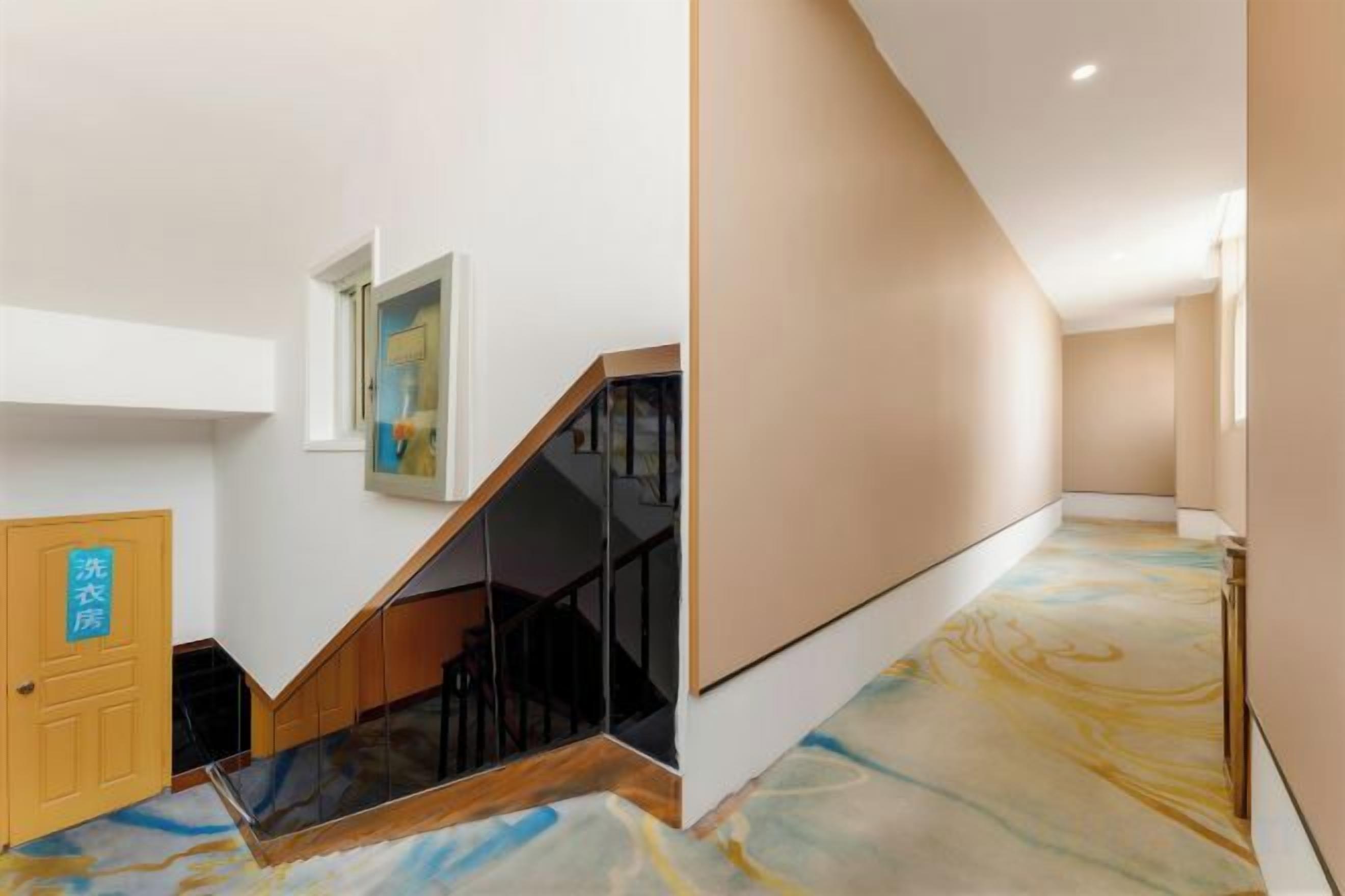 A hallway with a staircase, a door with a sign, and a painting on the wall.