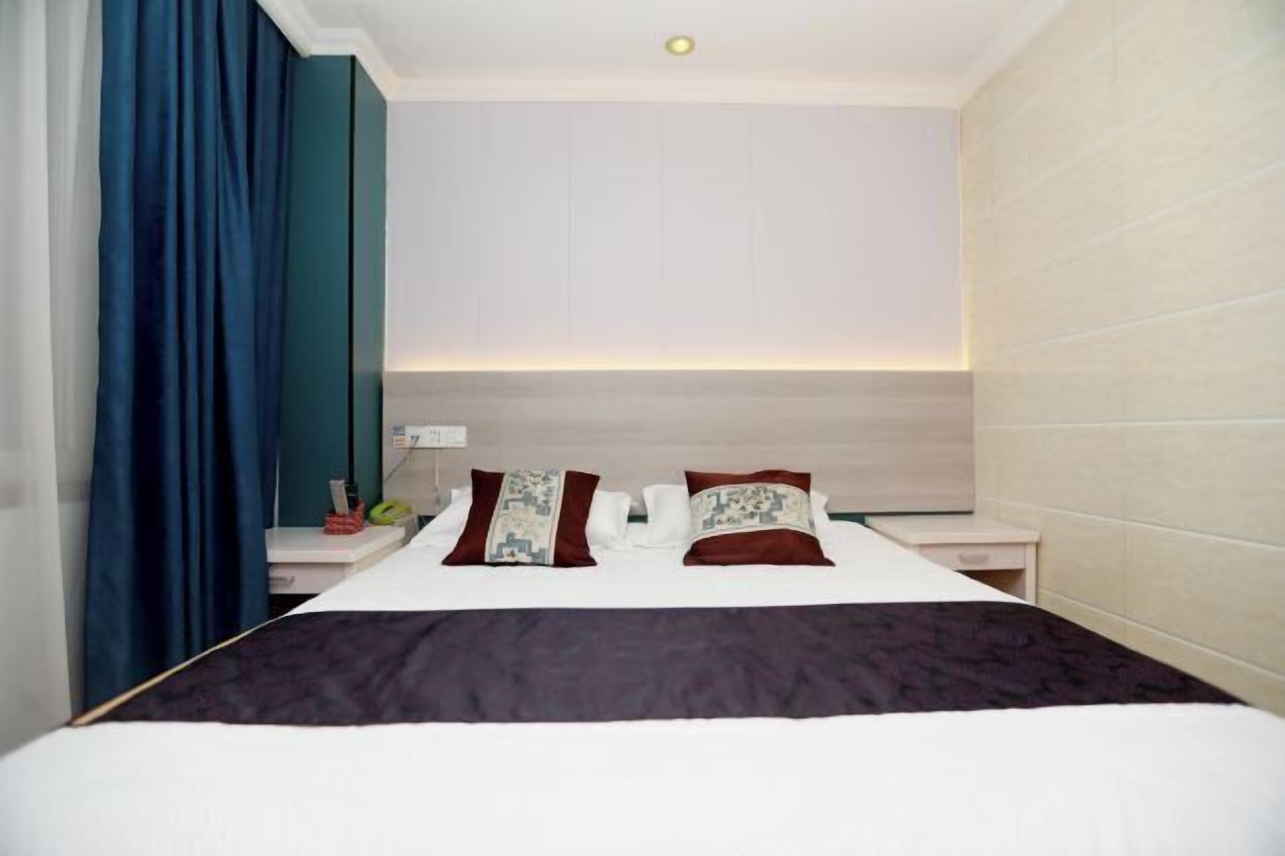Quarto de hotel moderno com uma cama grande, duas mesas de cabeceira, um criado-mudo e cabeceira com iluminação embutida.