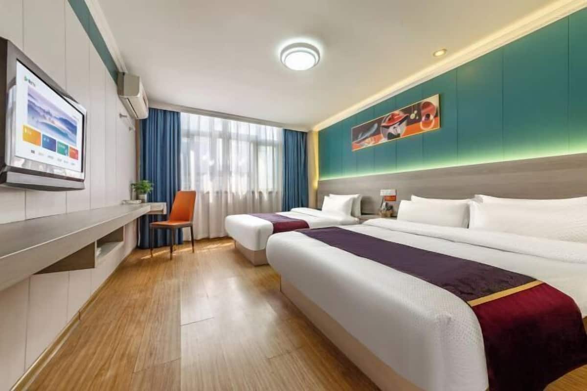 A hotel room with a bed, a desk, a chair, a TV, and a window with curtains.