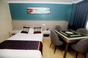 A hotel room with a bed, bedside tables, a desk with a green playing card, and a wall-mounted painting of a beach scene. - Changsheng Hotel (Nanjing)