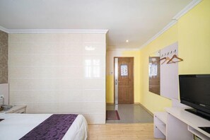 A hotel room with a bed, a television, and a door leading to a hallway. - Changsheng Hotel (Nanjing)
