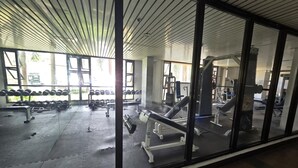 A gym with exercise equipment, large windows, and a ceiling with parallel lines. - Cozy Apartment Oasis in San Dionisio (Parañaque)