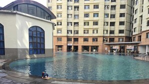 A swimming pool with a person sitting by the edge. - Cozy Apartment Oasis in San Dionisio (Parañaque)