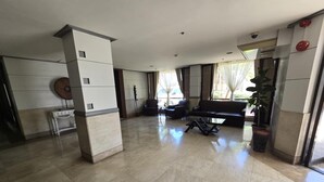 A spacious lobby with a marble floor, a black sofa, and a glass coffee table. - Cozy Apartment Oasis in San Dionisio (Parañaque)