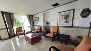 A lobby with seating arrangements, a reception desk, and a wall-mounted sign indicating amenities. - Cozy Apartment Oasis in San Dionisio (Parañaque)