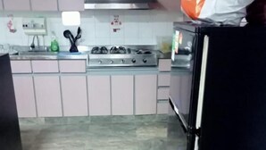 A kitchen with a gas stove, a refrigerator, and cabinets. - Hospedaje Cristiano Almagor (Bogotá)