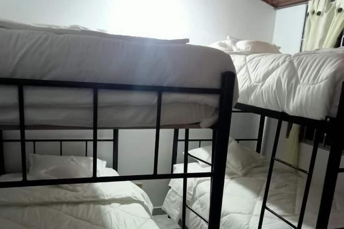 A bunk bed room with white bedding and black metal frames.