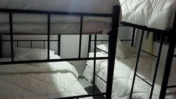 Habitación con literas, ropa de cama blanca y estructura metálica negra.