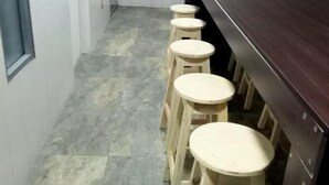 A narrow hallway with a dark wooden counter and four wooden stools. - Hospedaje Cristiano Almagor (Bogotá)