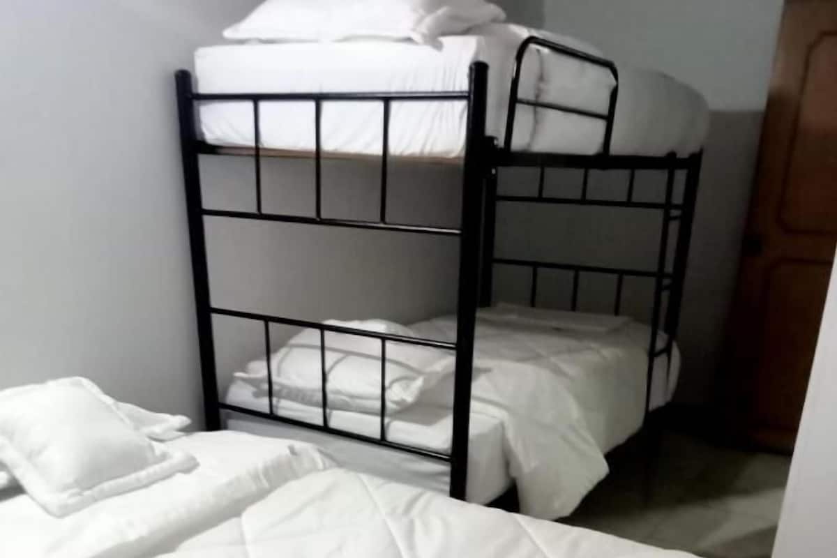 A bunk bed with white bedding and a lower bunk with a mattress and pillows.