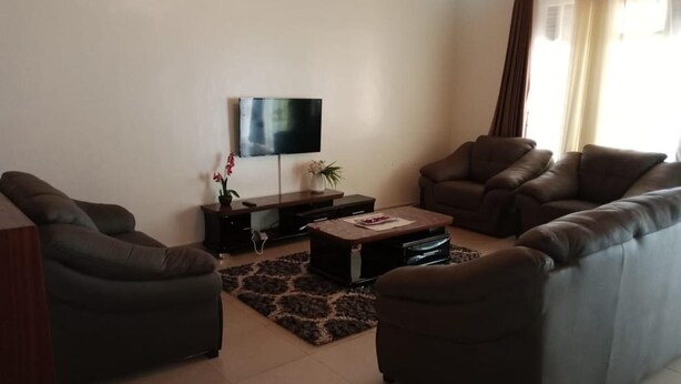 A living room with a flat-screen TV, two leather sofas, a coffee table, and a small side table with decorative items.