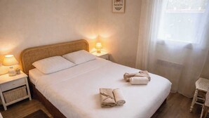 Ein ordentlich gemachtes Bett mit weißen Leinen, zwei Nachttischlampen und aufgerollten Handtüchern.
