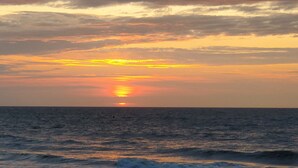 Ein Sonnenuntergang über dem Meer bei klarem Himmel und ruhiger Wasserfläche.