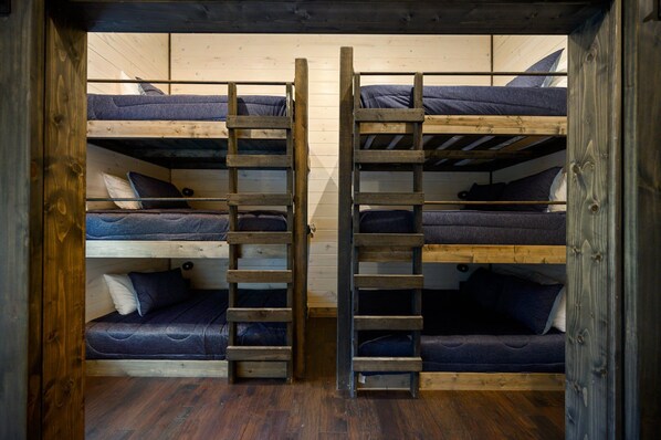 A bunk bed room with wooden ladders and a wooden floor.