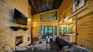 Ein Blockhaus-Interieur mit Kamin, einer großen Eckcouch und einem Essbereich.
