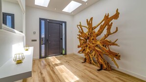 A modern interior with a wooden floor, a large abstract sculpture, and a dark door. - Villa Bolboreta by Villa Plus (Teguise)