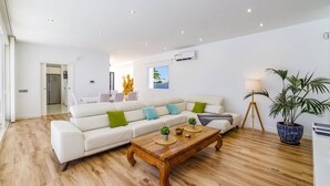 A modern living room with a white sofa, wooden coffee table, and potted plants. - Villa Bolboreta by Villa Plus (Teguise)