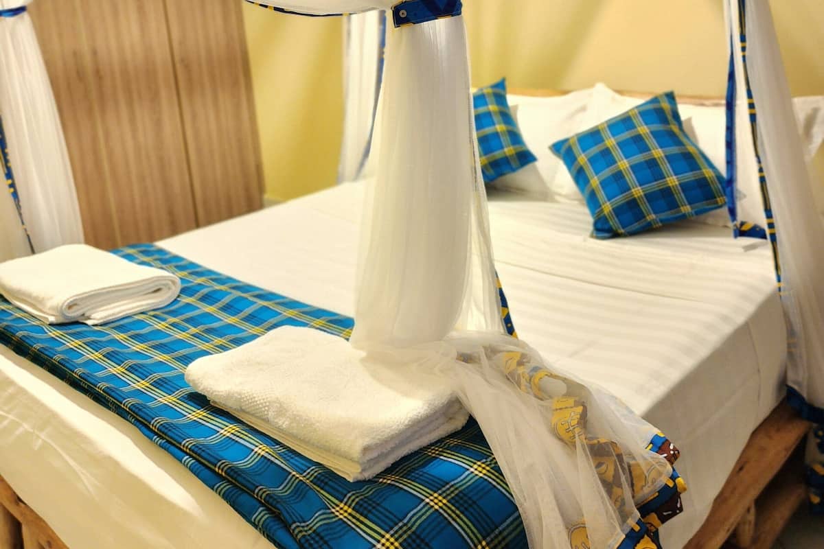 A bed with a canopy, blue and yellow plaid bedding, and a wooden headboard.