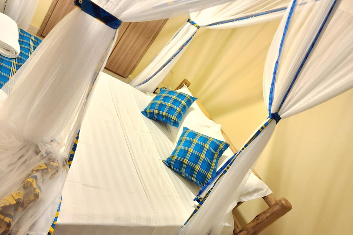 A room with four beds, each with a canopy. The beds are arranged in a square layout.