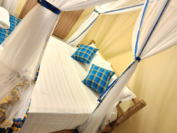 A room with four beds, each with a canopy. The beds are arranged in a square layout.
