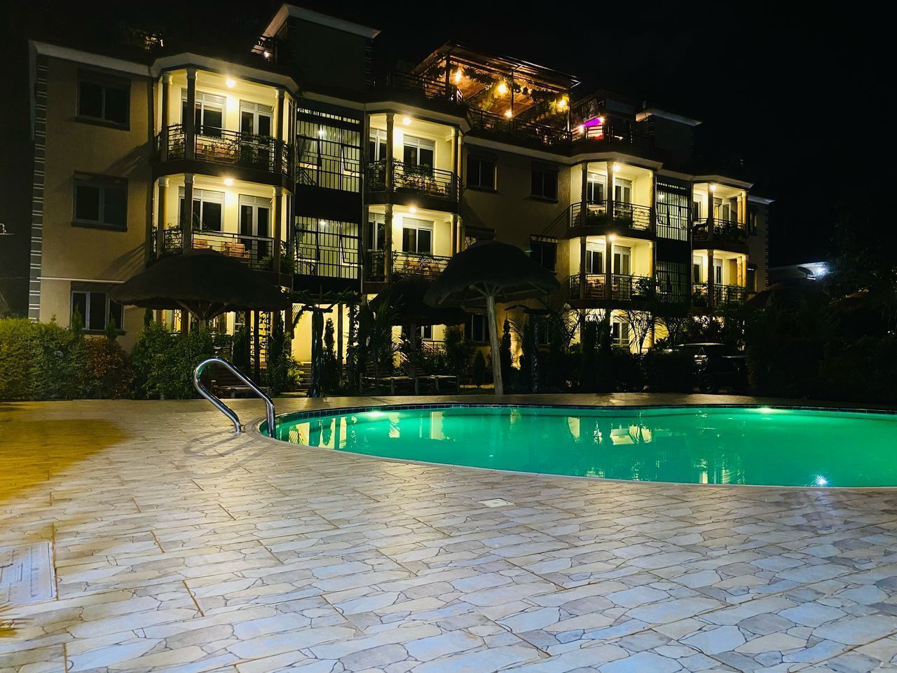 A multi-story hotel with a swimming pool, outdoor lighting, and balconies.