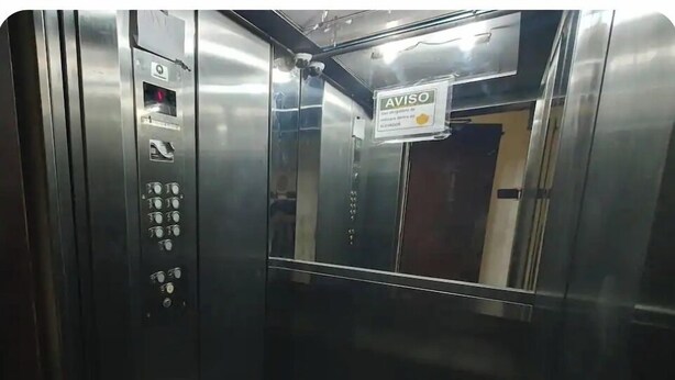 Interior metálico de un ascensor, con panel de control, señalización y puerta.
