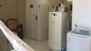 Un espacio habitable compacto con kitchenette, una puerta y una hamaca.