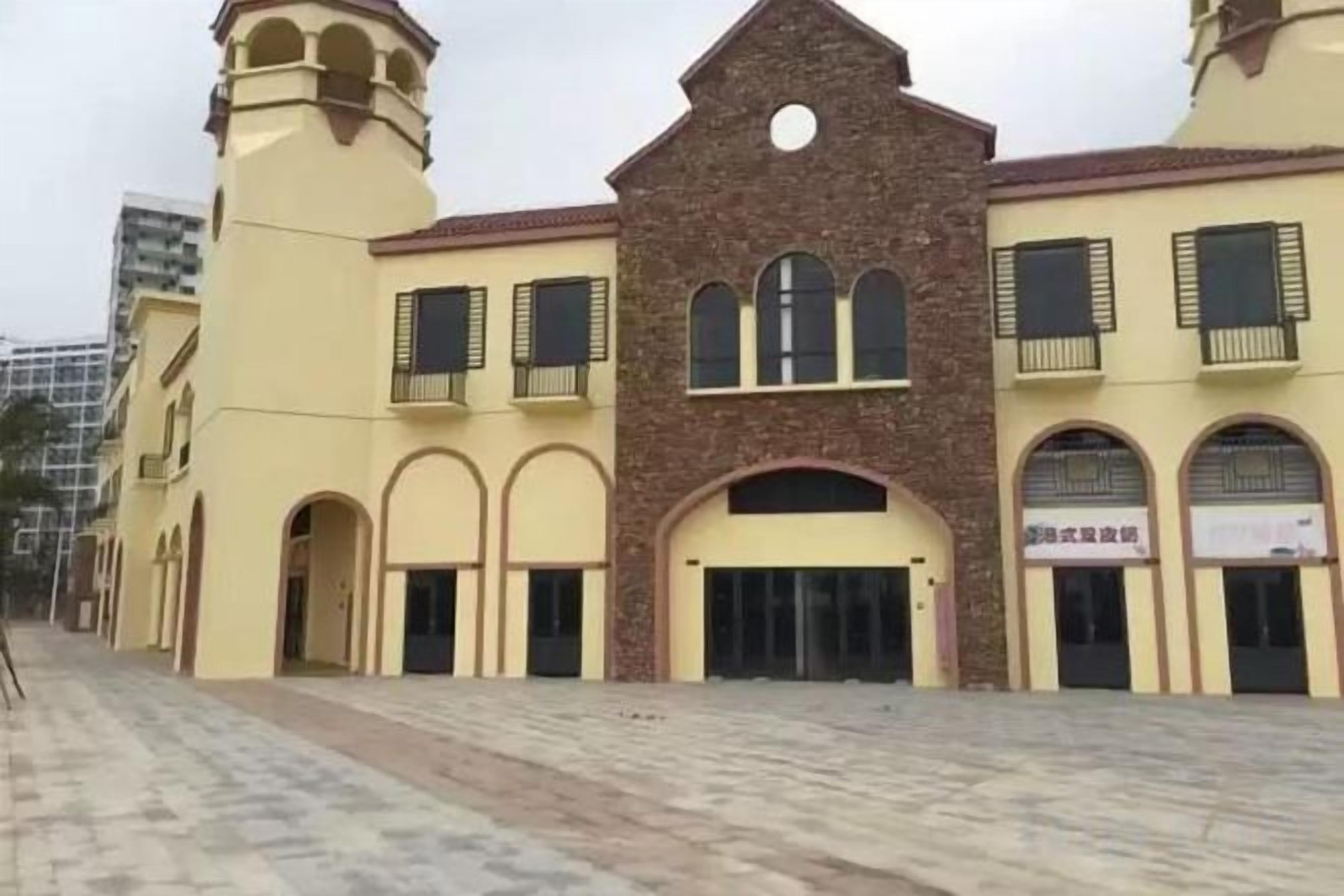 Un bâtiment doté d’une entrée centrale en arc de cercle, de nombreuses fenêtres et d’une tour située sur le côté gauche.
