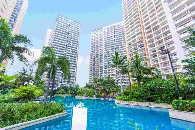 A residential building complex with a swimming pool surrounded by greenery.