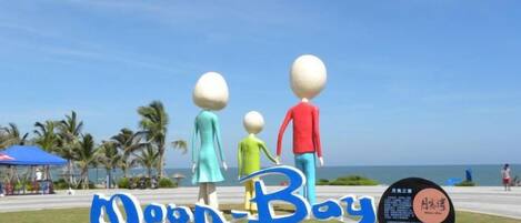 A beach sign with the text 'Moon Bay' and a family of figures.