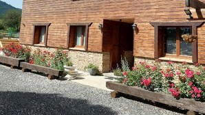 Un edifici de fusta de dues plantes, amb diverses finestres, fonamentació de pedra i un camí d'accés de grava.